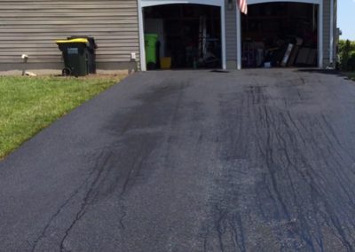 Freshly sealed driveway leading to a double garage with an American flag on the side.