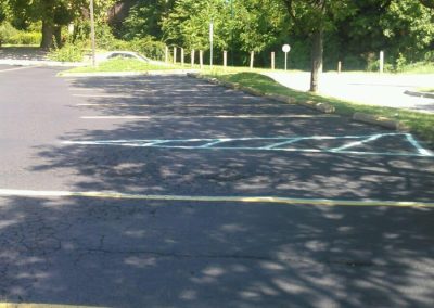 Empty parking lot with sunlight filtering through green trees.