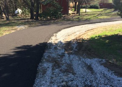 Paved road with white petals near red barn