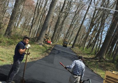Two workers paving a road with asphalt.