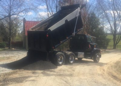 Dump truck unloading gravel on a sunny day.