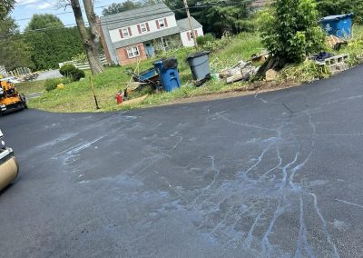 Freshly sealed asphalt driveway near suburban home